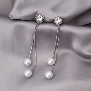 Detailed view of silver tassel earrings with delicate pearls on grey silk fabric