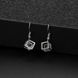 Macro shot of silver cube dangle earrings featuring a sparkling zircon stone inside
