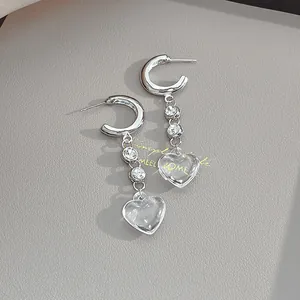 Macro shot of S925 silver C-shaped heart earrings with clear pendants and cubic zirconia