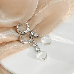 Detail shot of heart-shaped crystal pendant earrings with silver hoops and transparent beads