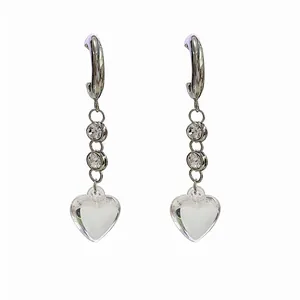 Detail of long tassel earrings with sparkling heart crystal and polished silver hooks