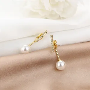 Close-up of elegant pearl drop earrings with sparkling rhinestones on champagne silk