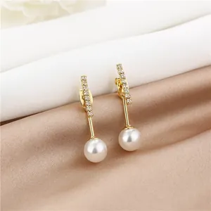 Detail of long drop earrings with gold base, sparkling crystals and lustrous pearls