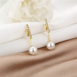 Close-up of elegant gold tassel earrings with rhinestones and white pearls on silk fabric