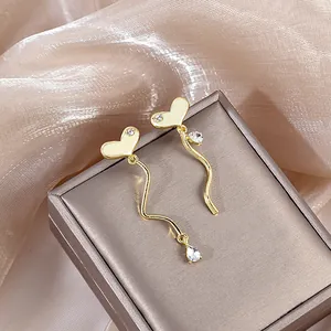 Detailed view of asymmetrical gold heart fringe earrings with sparkling crystals