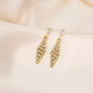 Close-up of gold geometric earrings with sparkling pavé crystals on champagne silk background