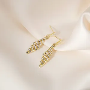 Detailed close-up of golden diamond-encrusted tassel earrings on elegant silk fabric