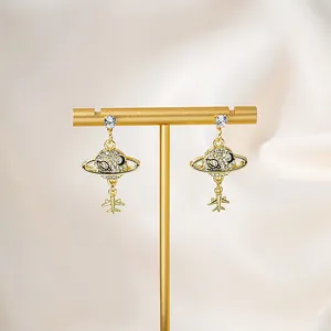 Macro view of gold Saturn planet and airplane earrings with sparkling zircon crystals