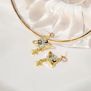 Detail of Saturn-shaped gold earrings with white crystals and star-shaped metal pendants