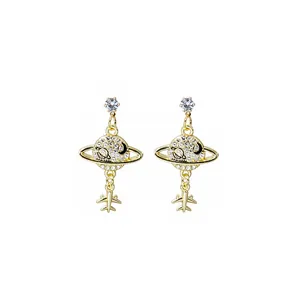 Macro detail of gold-plated planet and airplane dangle earrings with zircon pavé