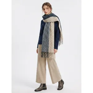 Woman in navy sweater and beige trousers wearing a matching color-block plaid scarf
