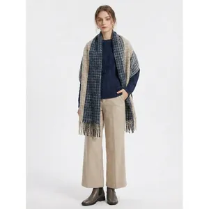 Navy and beige patchwork color block tassel scarf draped over a blue knit sweater