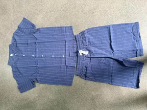 Navy blue striped linen set with short-sleeve shirt and drawstring shorts on a stone floor