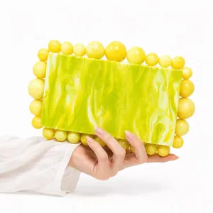 Detail of marbled acrylic evening clutch bag with yellow pearl bead trim