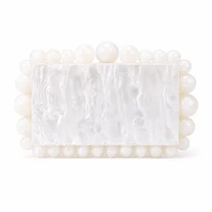 Detail of elegant pearl white evening bag with marble texture and round bead accents