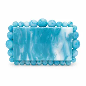 Detail of blue and white marble pattern acrylic box clutch with beaded edge trim