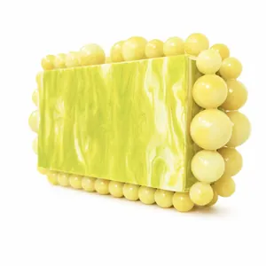 Detail of yellow-green marble acrylic clutch with large sphere beads along the edges