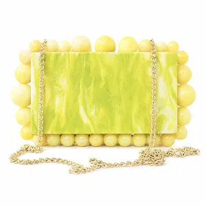 Detailed close-up of marble textured acrylic evening clutch with bead trim and gold chain
