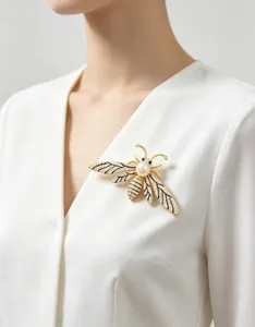 Detail of a luxury gold bee brooch with white pearls and sparkling crystals on clothing