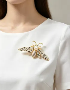 Detailed close-up of a luxury bee brooch with shimmering crystals and a large white pearl