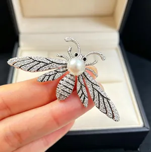 Detailed close-up of a silver bee brooch with sparkling crystals and a large white pearl