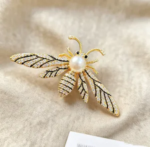 Detailed close-up of bee brooch with sparkling crystals and pearl on textured fabric
