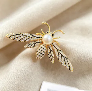 Macro shot of bee brooch with pearls and sparkling crystals on beige fabric