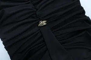 Detail of elegant black pleated dress featuring a stylish silver metal knot buckle
