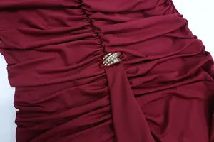 Close-up of ruched burgundy fabric with a metallic silver ring detail on the waist