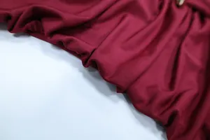 Macro detail of wine red ribbed fabric with an elegant gold metal ring buckle