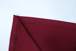 Detailed close-up of high-quality flatlock stitching and hem on burgundy knit dress fabric