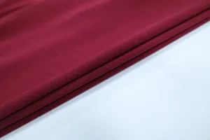 Detailed close-up of dark red fabric showing fine knit texture and elegant draping quality