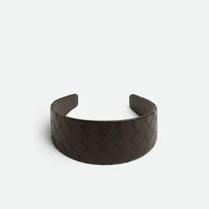 Close-up of deep brown woven leather headband featuring minimalist wide-brim texture