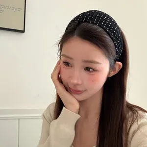 Detailed side view of a wide black polka dot headband with rhinestones on a female model