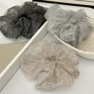 Detailed view of elegant pleated mesh hair scrunchies with sparkling glitter accents