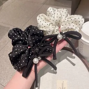Close-up of black and white polka dot hair scrunchies with pearls and ribbon bows