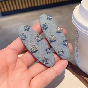 Close-up of denim fabric hair clips with star and heart rhinestone studs in hand