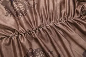Detailed close-up of brown printed satin fabric with ruched design and silk texture