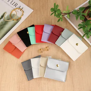 Multicolor PU leather jewelry pouches with golden snap buttons on wooden table
