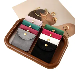 Microfiber jewelry pouch with gold snap button in multiple colors on a tray