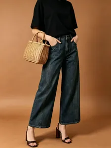 Dettaglio dei jeans a gamba larga a vita alta con cuciture verticali in blu scuro retrò