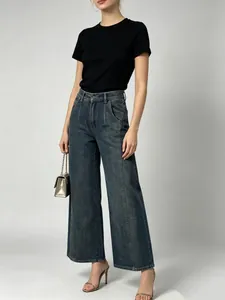 Dettaglio di jeans a gamba larga a vita alta con lavaggio vintage e cucitura frontale