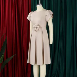 Detailansicht eines eleganten beigen Kleides mit 3D-Blumenverzierung und einem Plissee-Rock