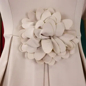 Detailaufnahme der 3D-Stoffblume mit goldenen Rändern auf dem aprikosenfarbenen Kleid