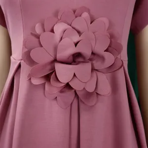 Makroaufnahme der 3D-Blumendekoration und des strukturierten Stoffes am rosa Kleid