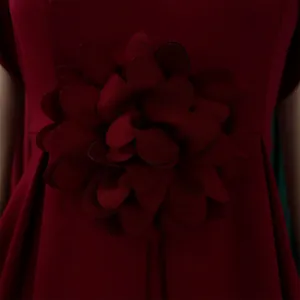 Nahaufnahme einer handgefertigten 3D-Stoffblume an einem eleganten weinroten Kleid