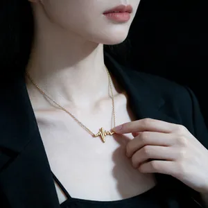 Detail of gold heartbeat pendant necklace worn by a model on a minimalist black background