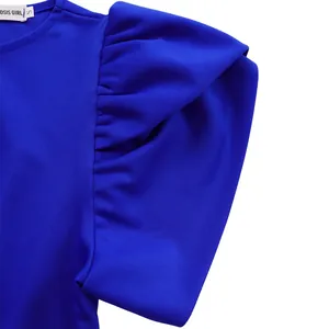Nahaufnahme der königsblauen Puffärmel-Textur und Markenetikett am sommerlichen Kleid