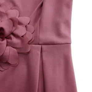 Detailansicht eines altrosa Kleides mit 3D-Stoffblume und Falten an der Taille