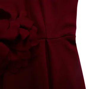 Detail eines weinroten Kleides mit strukturiertem Stoff und 3D-Blumenverzierung an der Taille